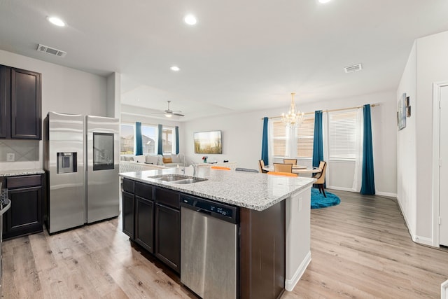 kitchen featuring light hardwood / wood-style floors, sink, an island with sink, stainless steel appliances, and ceiling fan with notable chandelier