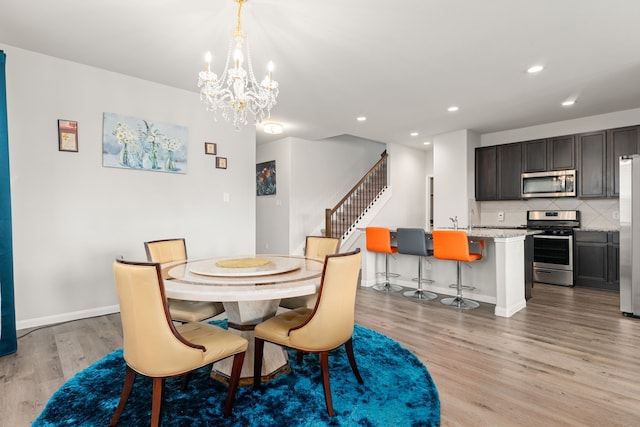 dining area with sink, light hardwood / wood-style floors, and a notable chandelier