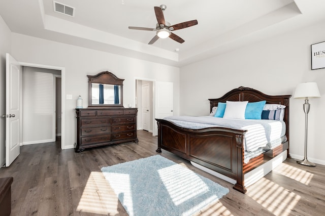 bedroom featuring ceiling fan, a tray ceiling, and hardwood / wood-style floors