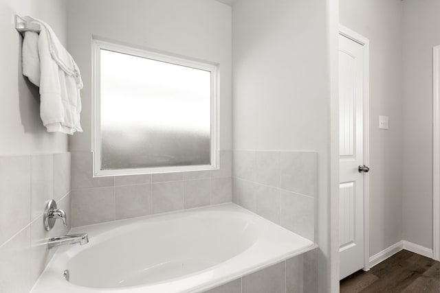 bathroom featuring a relaxing tiled tub and hardwood / wood-style flooring