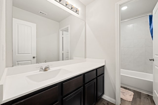 bathroom with hardwood / wood-style floors, vanity, and shower / bath combo