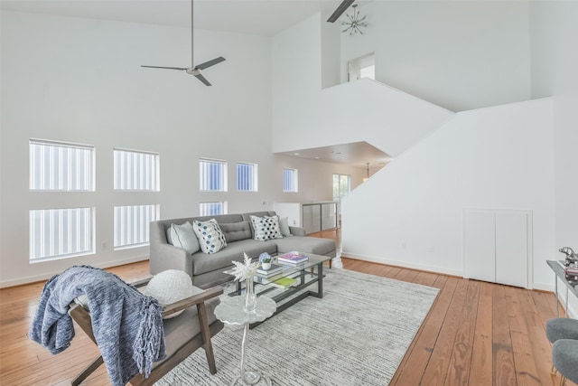 living room featuring a high ceiling, light hardwood / wood-style flooring, and ceiling fan