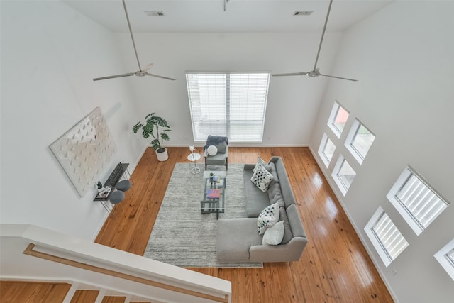 living room featuring hardwood / wood-style floors, ceiling fan, and a high ceiling