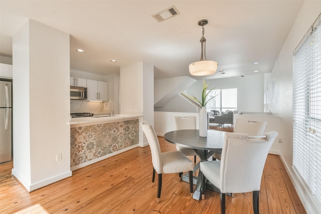 dining space with sink and light hardwood / wood-style flooring