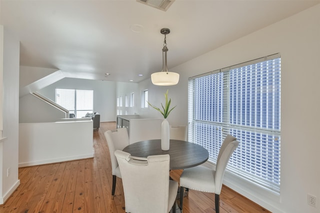 dining room with vaulted ceiling and light hardwood / wood-style flooring