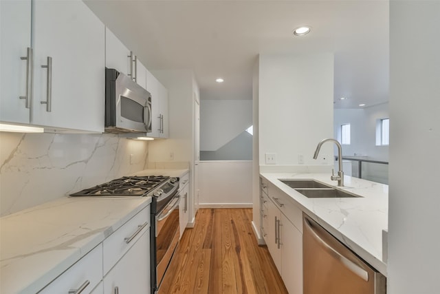 kitchen with light stone counters, sink, white cabinets, and stainless steel appliances