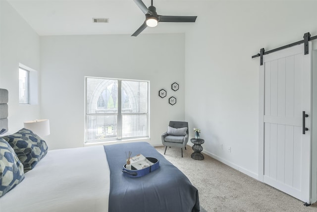 bedroom with ceiling fan, a barn door, and carpet floors