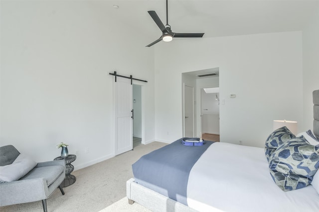 carpeted bedroom with a barn door, ceiling fan, and high vaulted ceiling