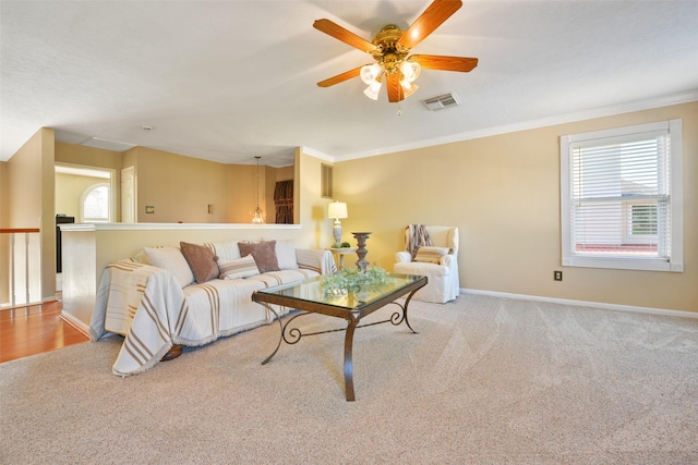 carpeted living room with ceiling fan and crown molding