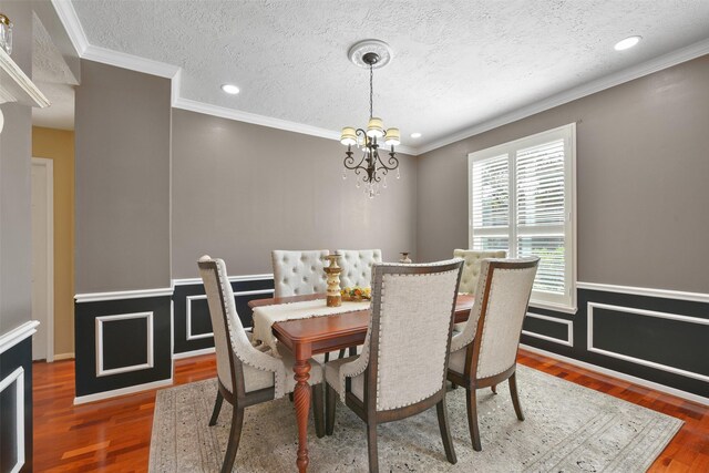 dining room featuring hardwood / wood-style floors, a textured ceiling, an inviting chandelier, and crown molding