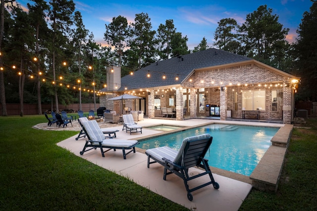 pool at dusk with a patio area, a yard, and an in ground hot tub