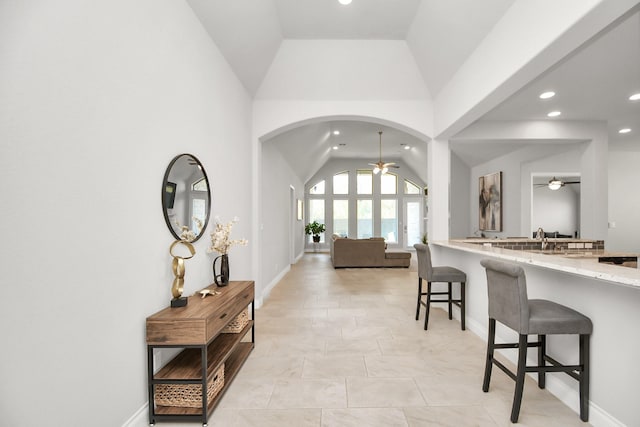 interior space featuring ceiling fan, light tile patterned floors, and high vaulted ceiling