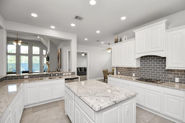 kitchen with white cabinets, a kitchen island, sink, and stainless steel gas cooktop