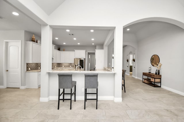 kitchen featuring white cabinets, a kitchen breakfast bar, stainless steel fridge with ice dispenser, and kitchen peninsula