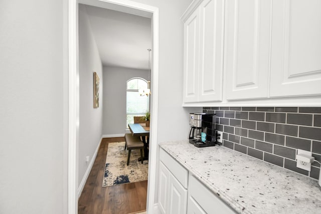 kitchen with white cabinets, light stone counters, backsplash, and hardwood / wood-style flooring