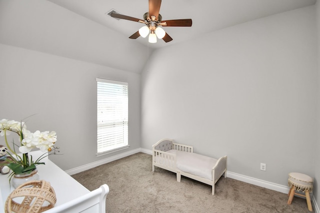 bedroom with ceiling fan, carpet, a nursery area, and vaulted ceiling