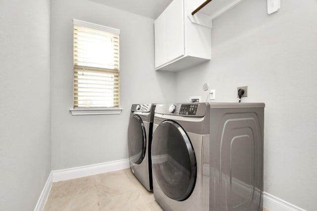 laundry area with washing machine and clothes dryer, light tile patterned floors, and cabinets