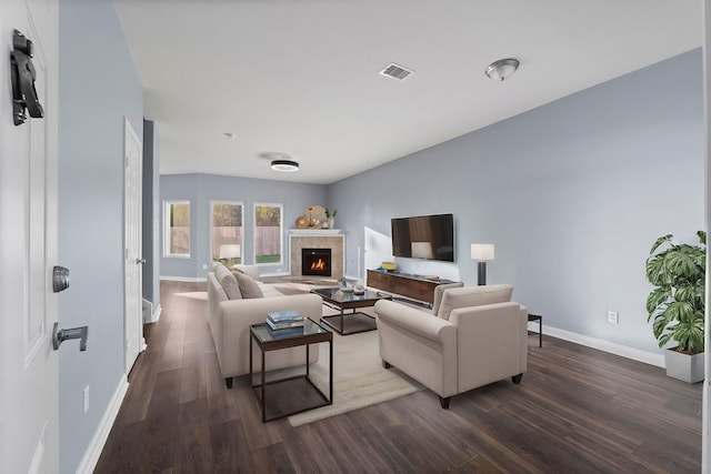 living room with a tile fireplace and dark hardwood / wood-style floors