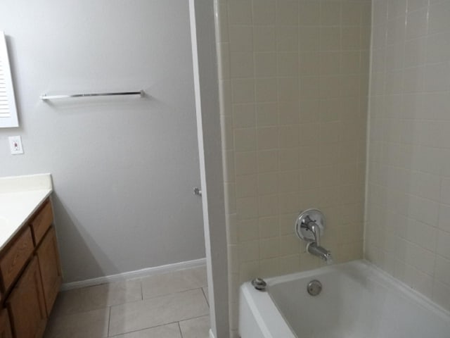 bathroom with tile patterned flooring, vanity,  shower combination, and baseboards