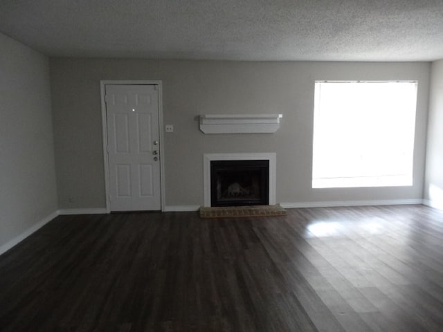 unfurnished living room with baseboards, a fireplace, wood finished floors, and a textured ceiling
