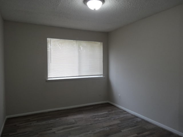 empty room featuring baseboards, a textured ceiling, and wood finished floors
