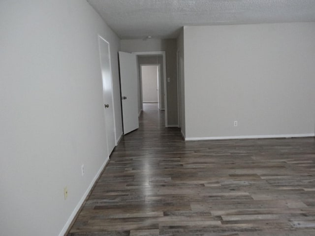 spare room with wood finished floors, baseboards, and a textured ceiling
