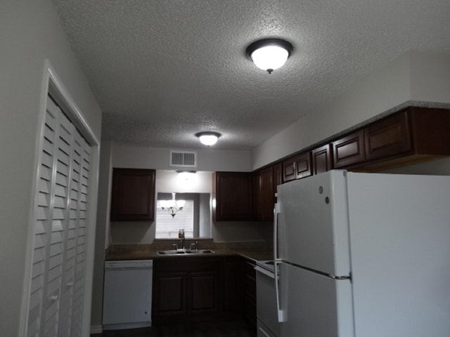 kitchen with a textured ceiling, visible vents, white appliances, dark brown cabinets, and a sink