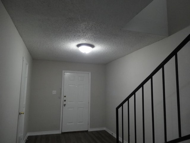 entryway featuring baseboards, dark wood-style flooring, and a textured ceiling
