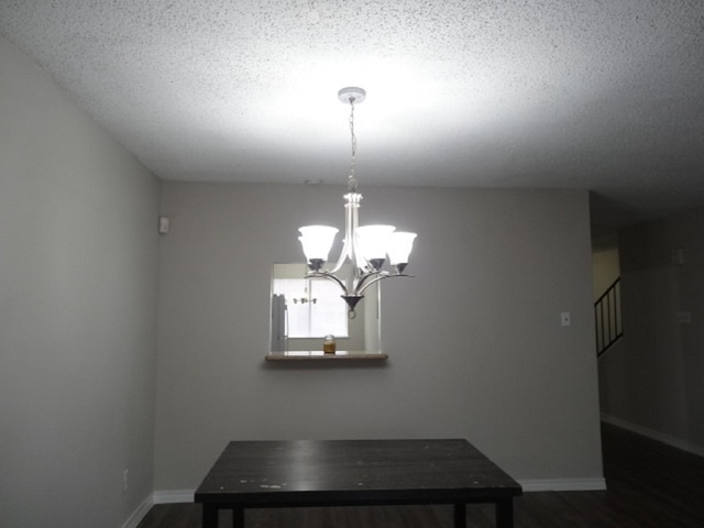 unfurnished dining area with stairway, baseboards, a textured ceiling, dark wood-style floors, and a notable chandelier