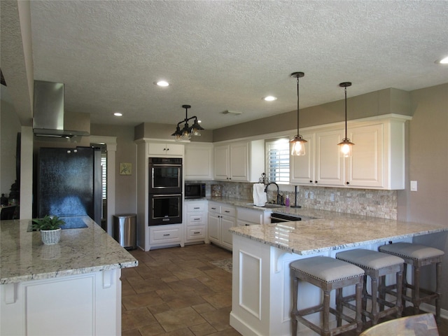 kitchen with white cabinetry, light stone countertops, wall chimney range hood, decorative light fixtures, and black appliances