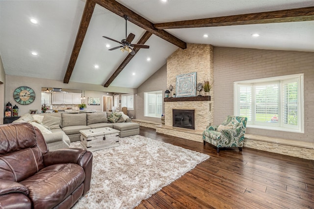 living room featuring a wealth of natural light, dark hardwood / wood-style flooring, a stone fireplace, and ceiling fan