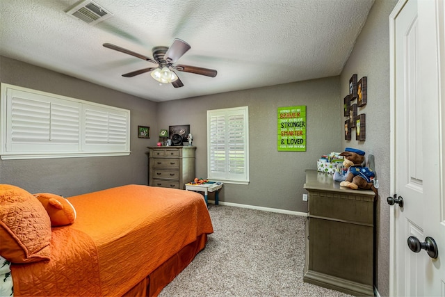 bedroom featuring light carpet, ceiling fan, and a textured ceiling