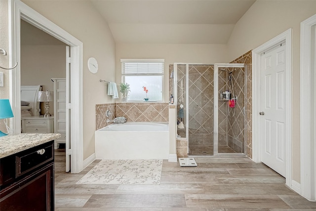 bathroom with hardwood / wood-style floors, vanity, independent shower and bath, and lofted ceiling