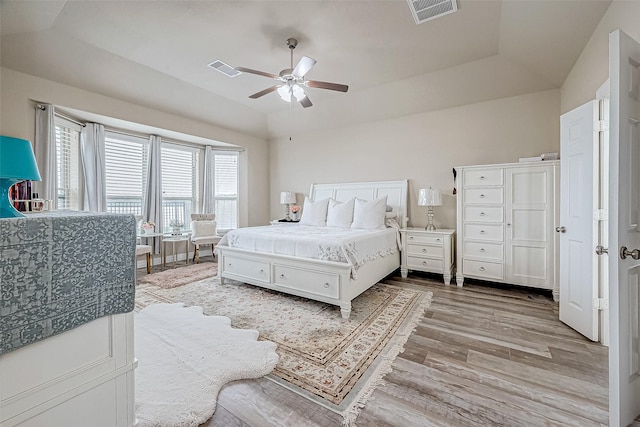 bedroom featuring a raised ceiling, ceiling fan, and light wood-type flooring