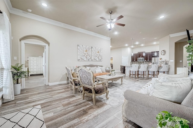 living room featuring ceiling fan, crown molding, and light hardwood / wood-style flooring