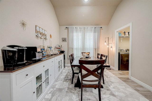 dining space with light hardwood / wood-style flooring, vaulted ceiling, and washer and clothes dryer