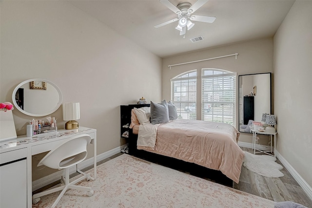 bedroom featuring a ceiling fan, visible vents, baseboards, and wood finished floors