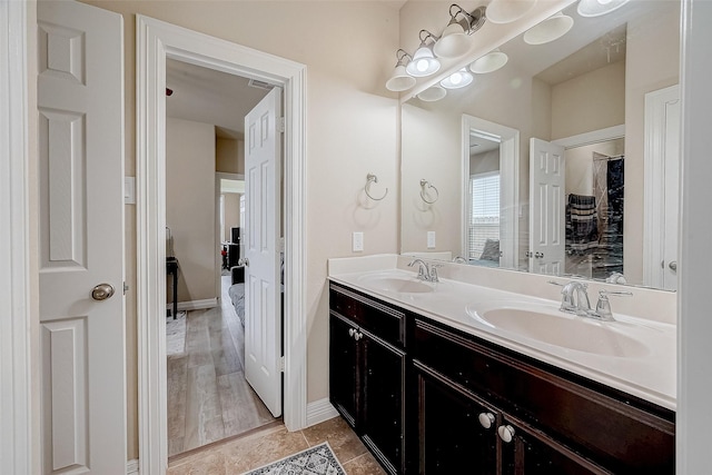 full bathroom featuring baseboards, double vanity, a sink, and tile patterned floors