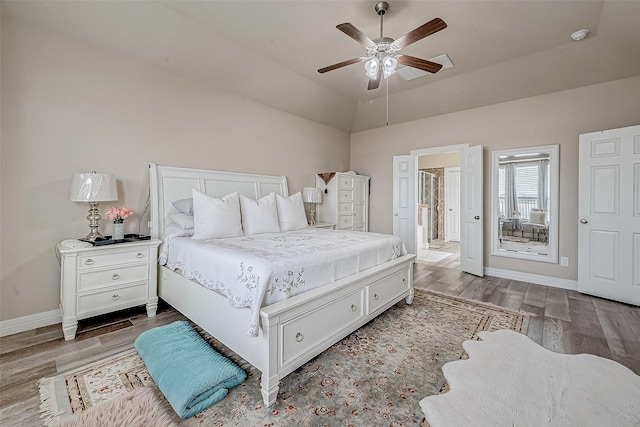 bedroom with lofted ceiling, ensuite bathroom, wood finished floors, a ceiling fan, and baseboards