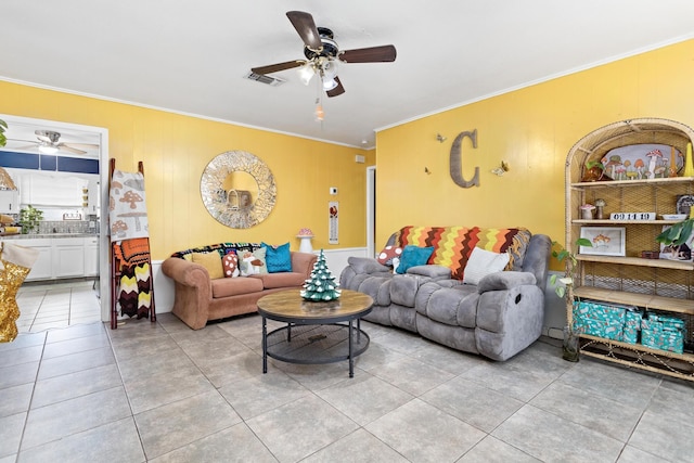 tiled living room with ceiling fan and ornamental molding