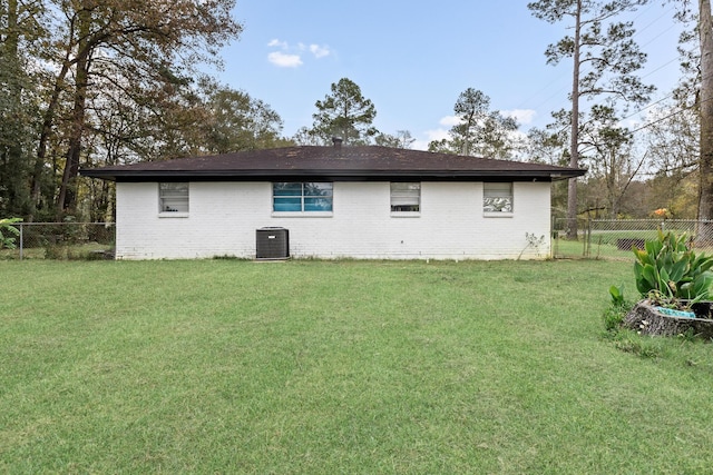 back of property with central AC and a lawn