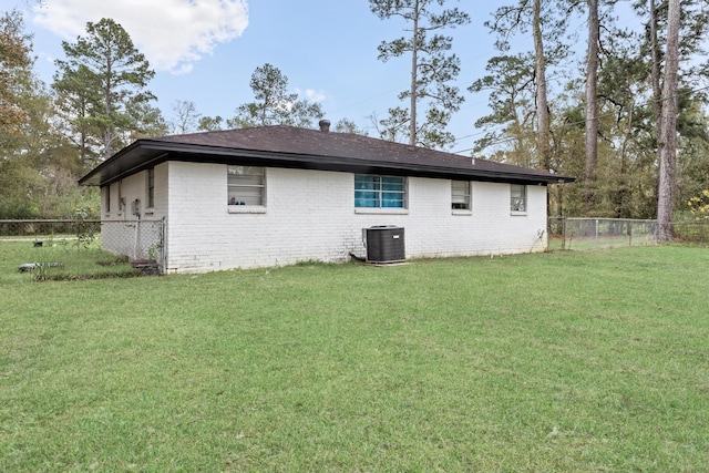 rear view of property with a lawn and central air condition unit