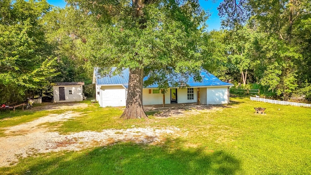 single story home with a porch, a storage unit, and a front lawn