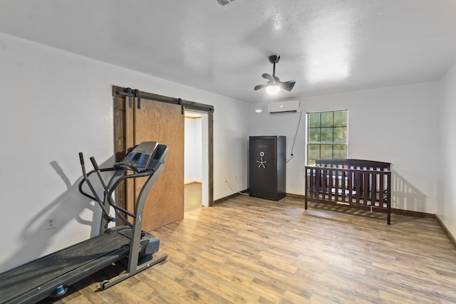 workout area featuring a barn door, light hardwood / wood-style flooring, and an AC wall unit