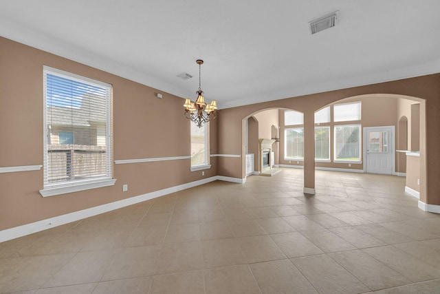 empty room featuring light tile patterned flooring, ornamental molding, and an inviting chandelier