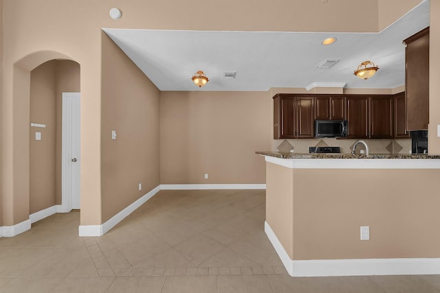 kitchen with range, light stone countertops, light tile patterned floors, dark brown cabinets, and kitchen peninsula