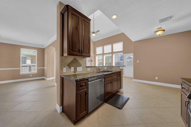 kitchen with dark stone countertops, sink, light tile patterned flooring, and stainless steel dishwasher