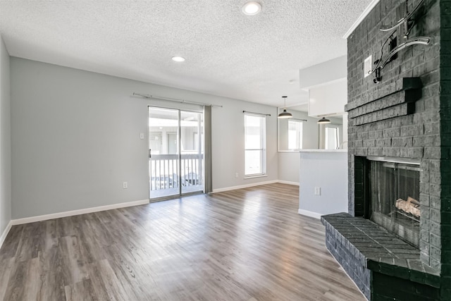 unfurnished living room with a fireplace, wood-type flooring, and a textured ceiling