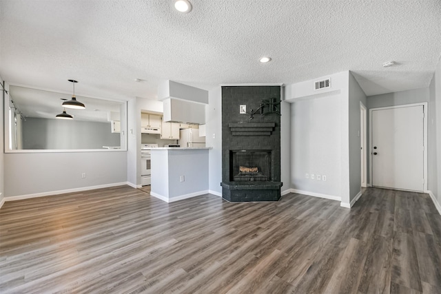 unfurnished living room featuring dark wood-type flooring, a textured ceiling, and a brick fireplace