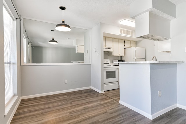 kitchen featuring dark wood-type flooring, kitchen peninsula, a textured ceiling, white appliances, and white cabinets